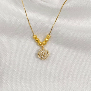 Detailed shot of gold clover pendant with sparkling pave diamonds and matte beads