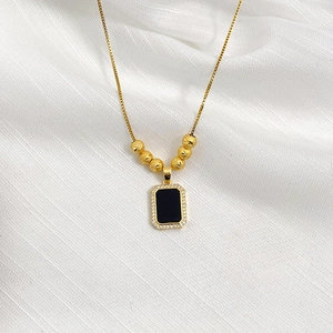 Detail of a gold rectangle pendant with black inlay and sparkling zircon border