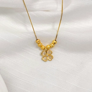 Detail of clover pendant with cat-eye stone, frosted beads and gold box chain necklace