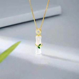 Elegante collana in bambù dorato con ciondolo in giada bianca e foglie verdi