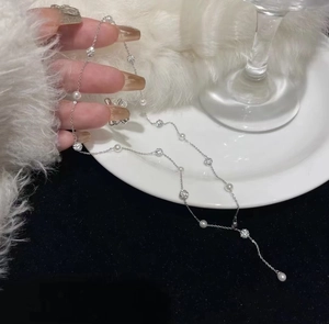 Close-up of silver Y-shaped tassel necklace featuring imitation pearls and sparkling pavé beads