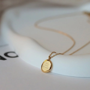 Detalle macro del collar de acero de titanio dorado con colgante ovalado cepillado y grabado