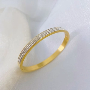 Bracelet jon jonc doré élégant avec trois rangées de zircones sur fond de maille blanche