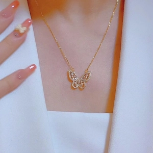 Elegante collar con colgante de mariposa dorada con circón en modelo con blazer blanco