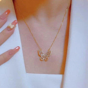 Elegante collar con colgante de mariposa dorada y circonitas brillantes en el cuello