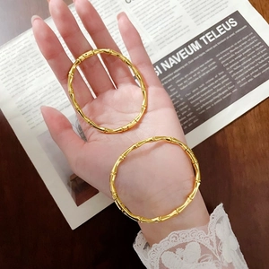 Coppia di bracciali aperti a forma di bambù in finitura oro 18k indossati sulla mano