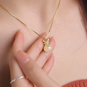 Elegante gouden geldbuidel ketting met witte chalcedoon op de nek van een model