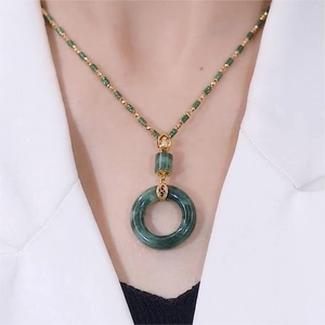 Detailed view of women's vintage green jade donut pendant necklace on a model's neck