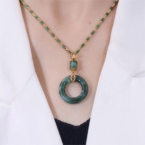 Close-up of a gradient green jade donut pendant necklace with elegant gold metal accents