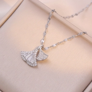 Silver ginkgo leaf pendant necklace with shimmering zircon stones on beige leather