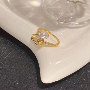 Elegant gold pearl ring with cubic zirconia accents on white textured tray display