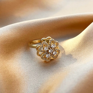 Detail of a rotating clover flower ring in gold finish with sparkling pavé crystals