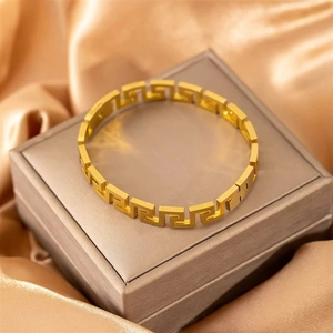 Poliertes goldfarbenes Titanstahl-Armband mit griechischem Muster auf Geschenkbox