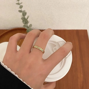 Goldener Titanstahlring mit schwarzem Mäandermuster getragen am Finger am Tisch