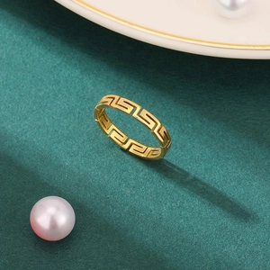 Eleganter goldener Ring mit griechischem Mäander-Muster auf dunkelgrünem Hintergrund