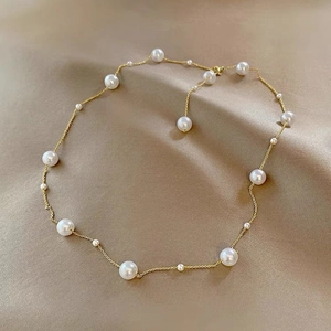 Elegante gouden parelketting met diverse maten op een achtergrond van champagne satijn