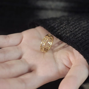 Titanium steel ring with Roman numeral hollow design worn on hand with black knit background