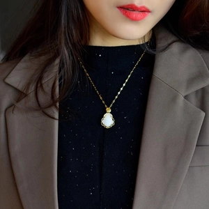 Elegant gold Buddha pendant necklace with white jade and sparkling zircon on model