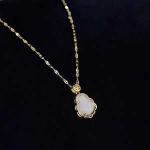Close-up of a white jade Buddha pendant with a gold clasp featuring a Fu character