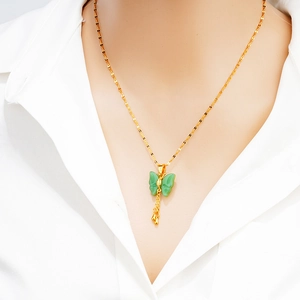 Elegant gold butterfly necklace with green faux jade wings and tassel on a female model