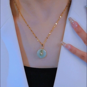 Collana a catena dorata con pendente in giada verde indossata da una modella raffinata