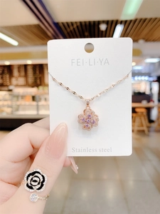 Detailed macro view of rotatable purple four-leaf clover pendant on rose gold necklace