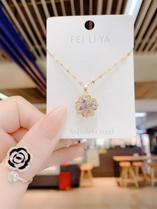 Detail of a rotating purple clover pendant in stainless steel displayed on a brand card