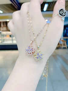 Close-up of rotatable four-leaf flower necklaces in rose gold and gold with purple zircons