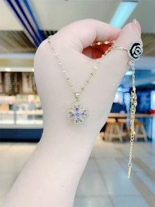 Close-up of rotatable purple four-leaf clover pendant in gold finish with crystals