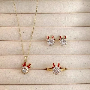 Three-piece gold reindeer jewelry set with red antlers and clear crystals in a beige box