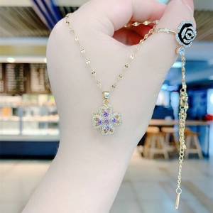 Rotating gold necklace with purple four-leaf clover pendant and sparkling crystals