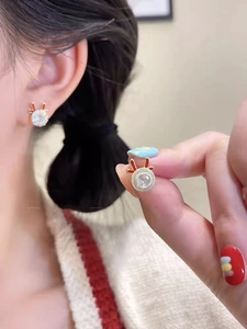 Close-up of golden reindeer stud earrings with crystal stone and red antler detail