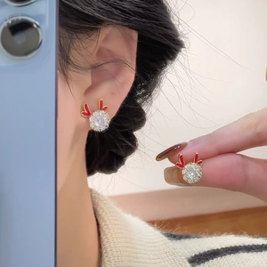 Close-up of reindeer antler earrings featuring clear zircon clusters and red enamel detail