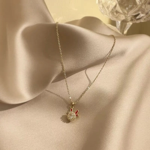 Detailed view of a golden rabbit necklace with sparkling zircon and red enamel on satin