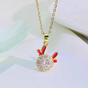 Macro view of gold bunny pendant with red enamel ears and sparkling crystal body