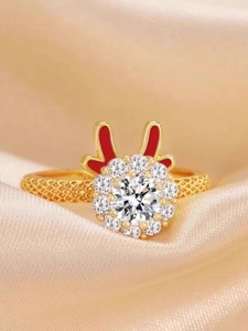 Close-up of golden rotating ring with red dragon ears and diamonds on champagne silk