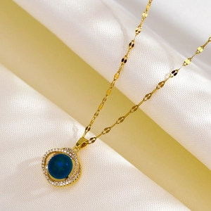 Bird nest pendant necklace with blue center stone and pave crystals in golden finish
