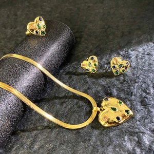 Detail of gold heart jewelry set with multi-colored stones and snake chain necklace