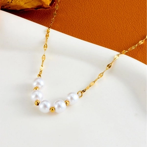 Elegante collar de acero de titanio dorado con cinco perlas blancas en bandeja blanca