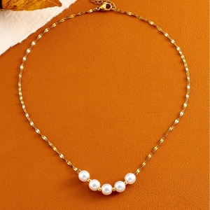 Elegante collar de acero de titanio dorado con cinco perlas blancas sobre cuero naranja