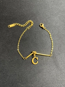 Makroaufnahme von vergoldetem Edelstahl-Knotenarmband mit C-Anhänger und S.steel-Punze