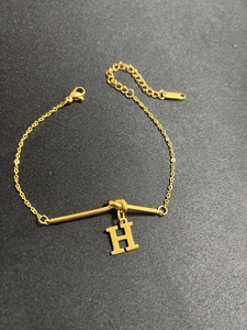 Makroaufnahme der goldenen Knotenkette mit H-Buchstabenanhänger und verstellbarem Verschluss
