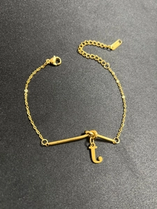 Detail der goldenen Gliederkette mit minimalistischem t-Anhänger und Karabinerverschluss