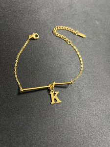 Detail der goldenen Titanstahl-Armkette mit K-Anhänger und verstellbarem Karabinerverschluss