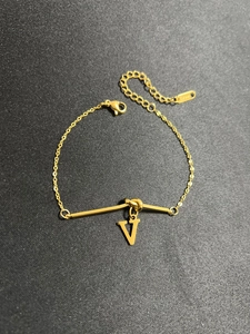 Makro-Detail von goldenem Edelstahlarmband mit V-förmigem Anhänger und sicherem Verschluss