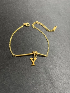 Detail eines vergoldeten Kettenarmbands mit horizontalem Stab und Buchstaben-Y-Anhänger