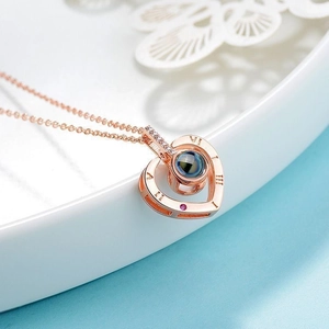 Macro detail of rose gold heart necklace with Roman numerals and blue center stone