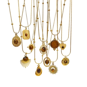 Macro shot of assorted vintage gold necklaces with natural brown tiger eye stone pendants