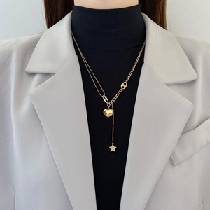 Gold layered heart and star pendant necklace on model with asymmetrical chain style