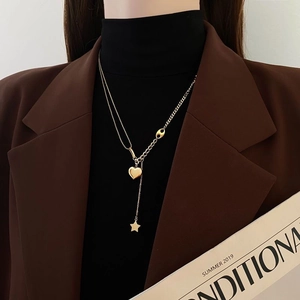 Detailed close-up of double layer gold necklace featuring star and heart pendants
